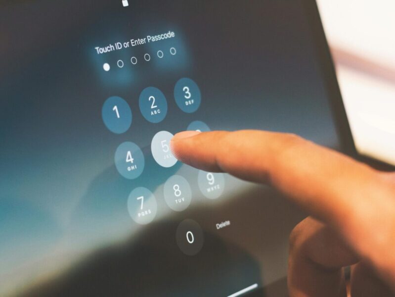 Close-up of a finger entering a passcode on a smartphone security screen.