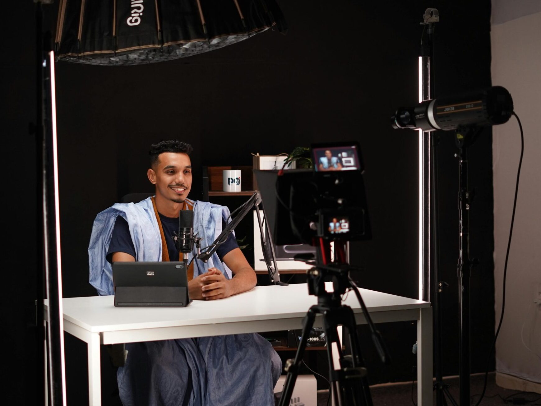 Young man recording a video in a professional studio with lighting and camera equipment.
