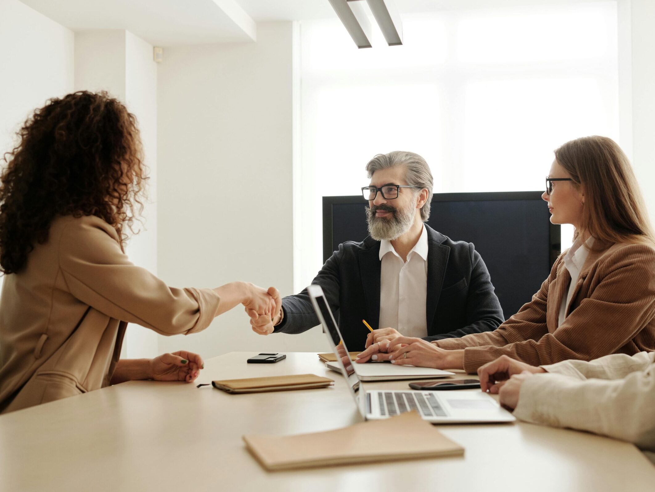 Colleagues in an office celebrating a successful negotiation with a handshake.