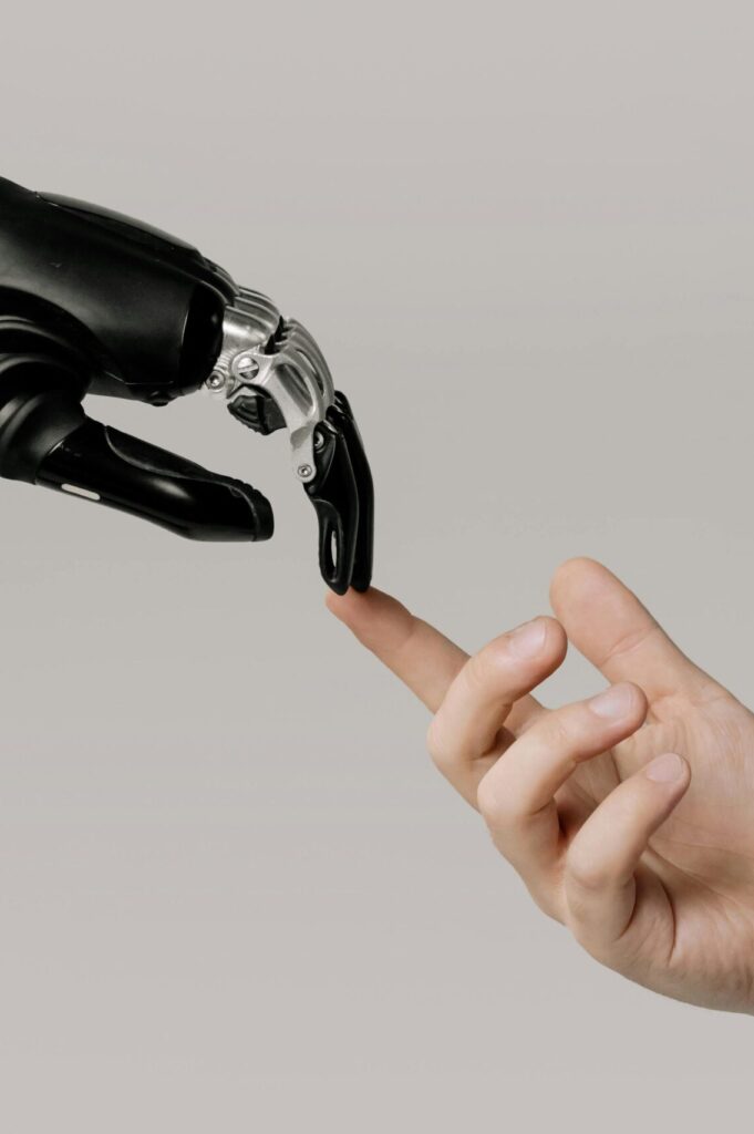 A human hand with tattoos reaching out to a robotic hand on a white background.
