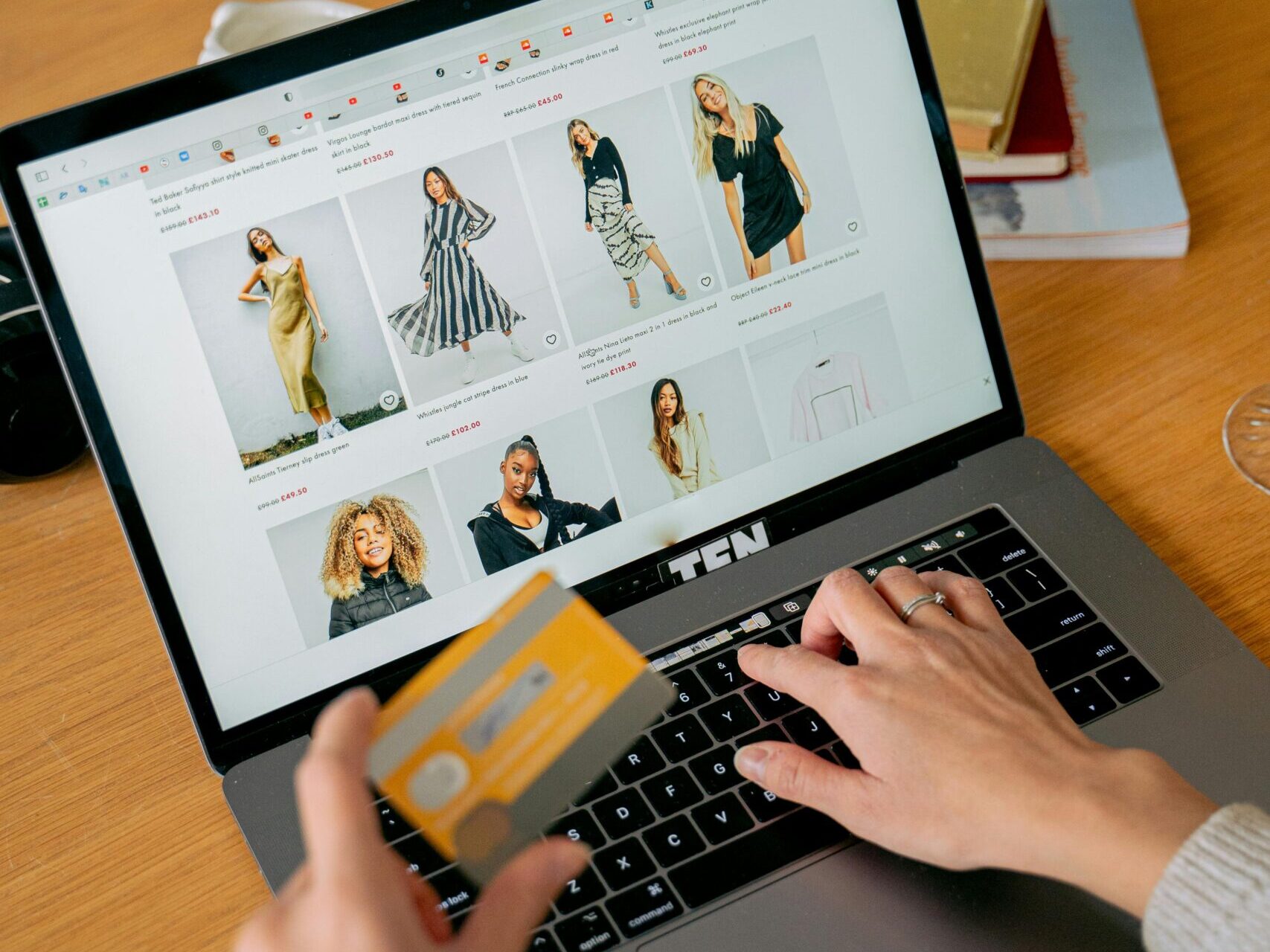 A woman makes an online purchase using a credit card on her laptop, browsing an online fashion store.