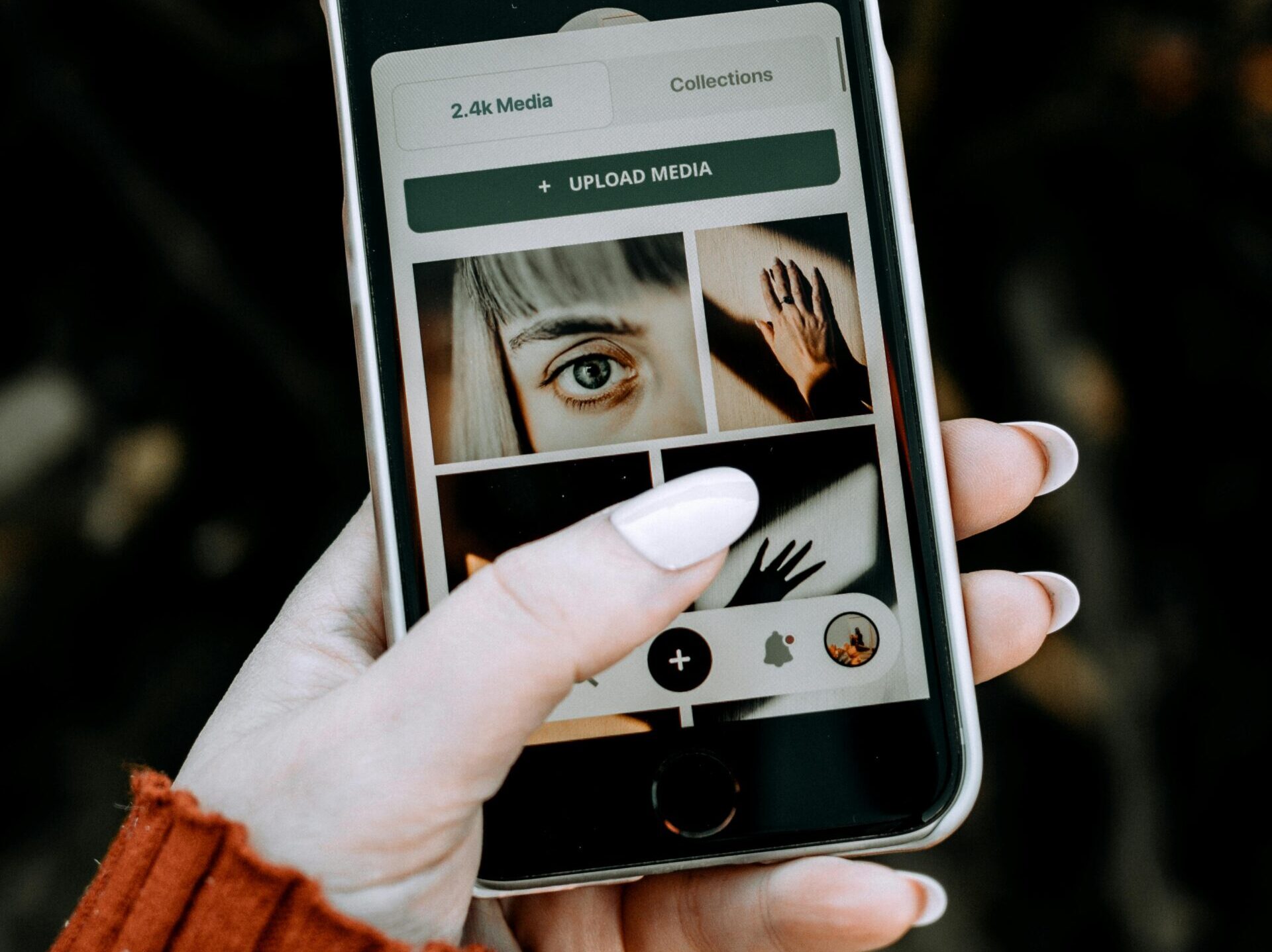 A hand holding a smartphone displaying a photo app with diverse media.