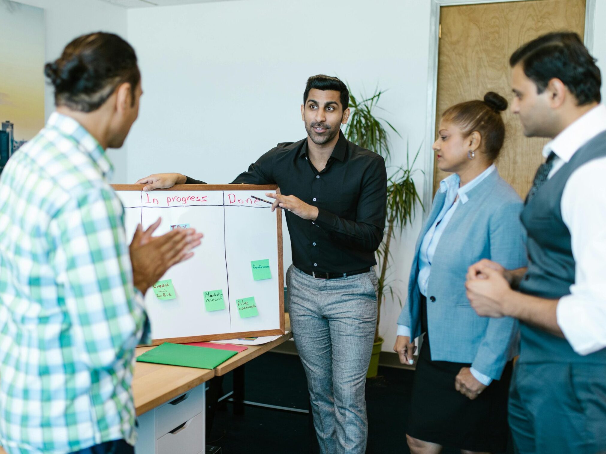 Diverse team discussing project progress with a board in a modern office.