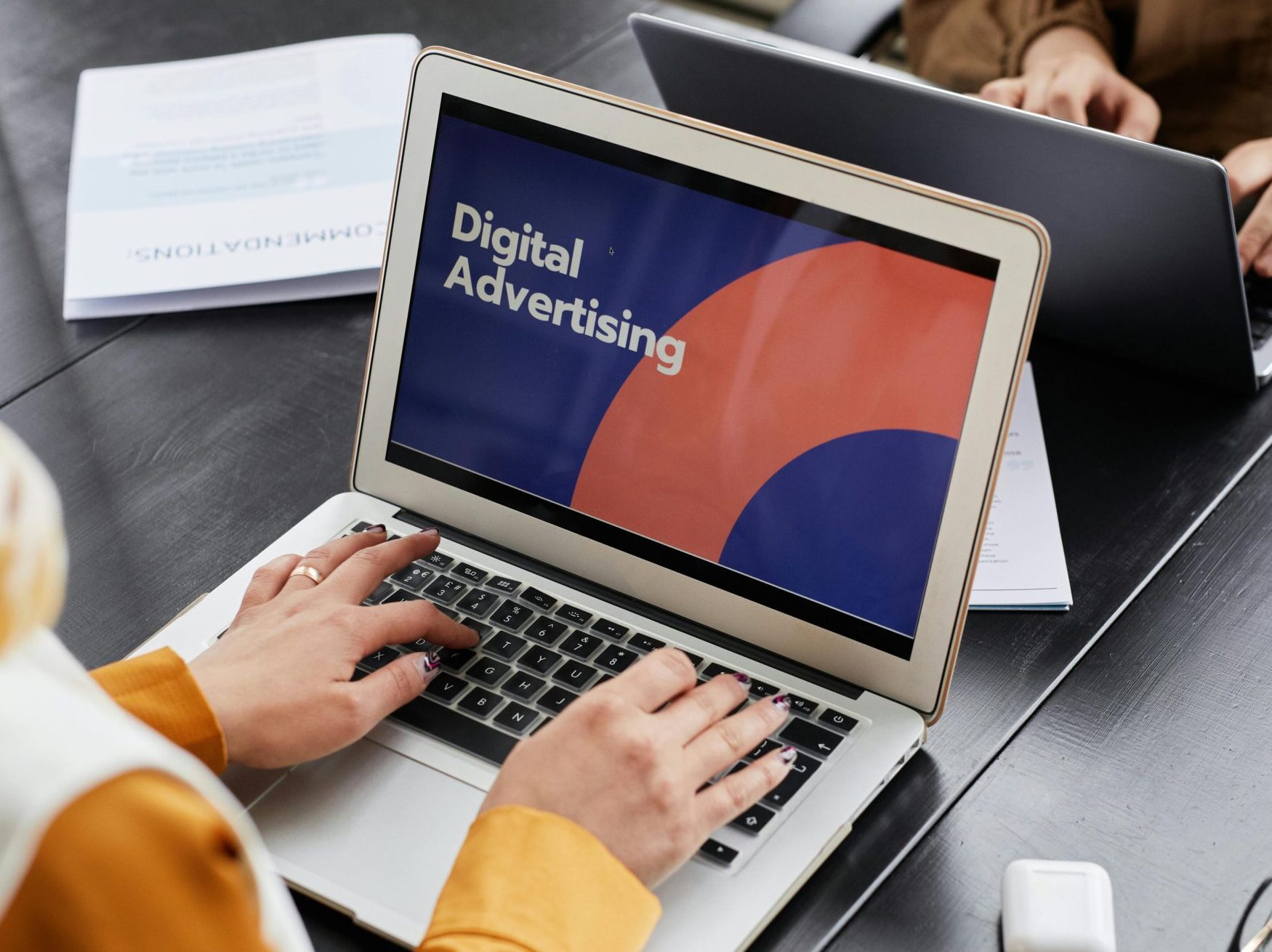 Two professionals work on laptops focusing on digital advertising in an office setting.