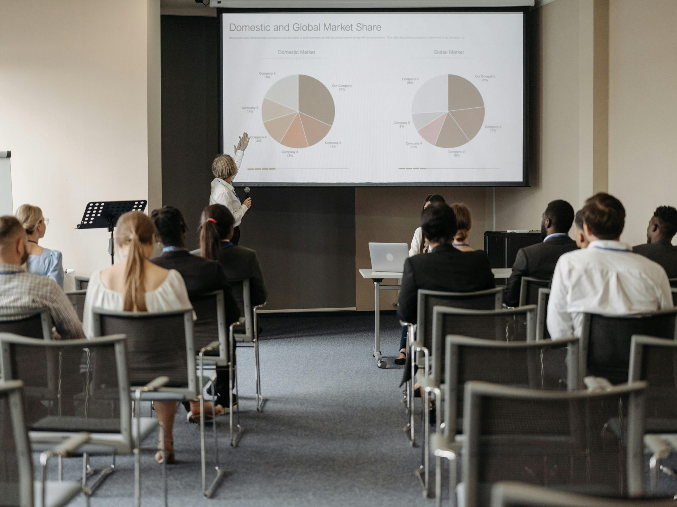 Business conference with diverse audience and speaker presenting market data.